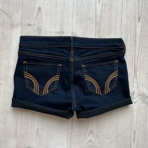 Lågmidjade mörkblå hollistershorts - Lågmidjade jeansshorts från Hollister som jag har gjort om från ett par byxor. Storlek W27 L29 och är lite små på mig som brukar ha S eller M. Tvärs över midjan är det ca 37 cm + stretch. Fint skick. Använd gärna köp nu!