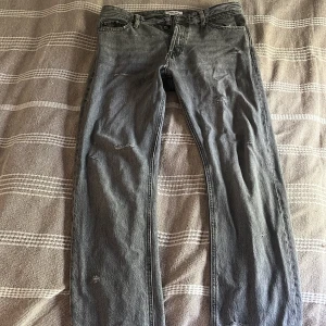 Grå jeans - Ett par gråa jeans från jack n jones, dem har lite slitningar som jag gjort själv för att jag tycker d ä snyggt, dock har det blivit ett hål mellan benen. 