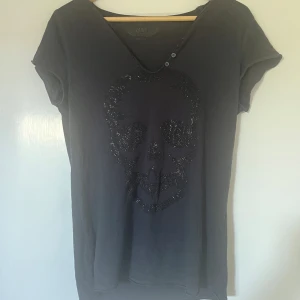 Zadig Voltaire T-shirt  - Jätte snygg T-shirt från Zadig Voltaire med en döskalle på. Har inga slitningar och alla knappar på krafen. Diamanterna är intakta å saknas inga. 🩷🩷Köpte för 900kr å den finns inte kvar på deras hemsida längre. Säljer för 400kr