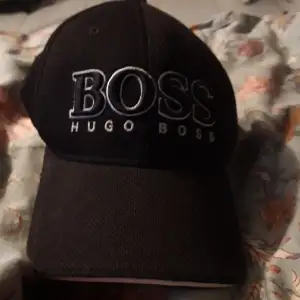 En hugo boss keps ganaka sliten och spännaren är sönder och det är lite tyg som sticker ut men den är köpt på hugo boss 