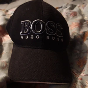 Hugo boss keps - En hugo boss keps ganaka sliten och spännaren är sönder och det är lite tyg som sticker ut men den är köpt på hugo boss 