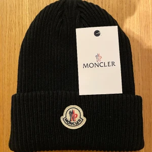 Moncler mössa - Perfekt skick med plastpåse över samt tags, har 1 i denna färg. Skriv privat för frågor! (Svart)