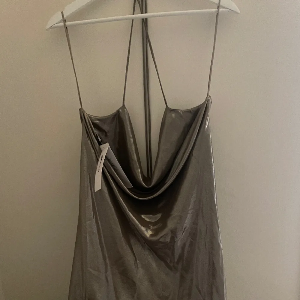 Miniklänning i silkes med ett litet djup i ryggen. Halterneck knytning. Inte använd, prislappen är kvar.. Klänningar.