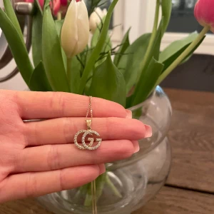 Halsband hängsmycket  - Hängsmycke med GG logga i älta guld 