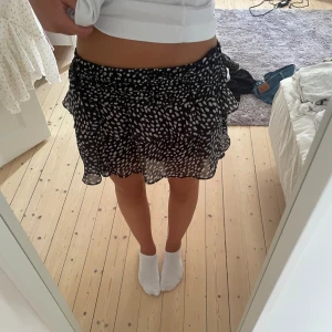 Prickig volangkjol  - Super snygg volangkjol i prickigt mönster!! Är i nyskick och från Chelsea🖤🤍Storlek XS men mycket stretch i midjan och går att vika ned!