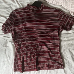 Turtleneck T-shirt  - Vinröd topp med vita ränder. Fint skick, alldrig använd.  Materialet är liknande till badkläder ( vet inte vad det heter men hoppas ni förstår 😭🙏 )  Ni får gärna skriva om det e nått, pris kan alltid diskuteras 😊💕