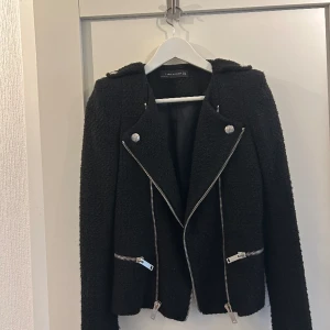 Zara Blazer / Kavaj  - Svart Blazer/Kavaj från Zara storlek S. Silvriga dragkedjor och knappar. Köpt för 1000 kr. Använd 2 gånger, fint skick, tyget blir lite luddigt när man använder den, se bild på ärmen. 2 små fickor, inbyggda axelvaddar. Djur-och rökfritt hem.