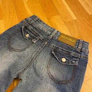 Blåa bootcut jeans med knapp fickor på baksidan och med dragkedja på framsidan. 