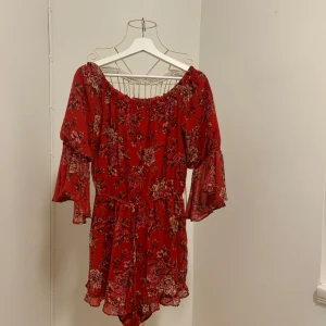Off-shoulder playsuit - Röd playsuit med blommönster, kan bäras off shoulder eller dras upp över axlarna.   Använd 1 gång, jag köpte denna i American Eagle Outfitters flagshipbutik i Hongkong där den var en limited edition för kinesiska nyåret 2018.