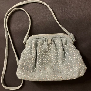 Handväska i jeans med diamant detaljer  - En gullig handväska från Zara i Paris. I blå/grått jeanstyg med silver/diamanter, använd 5-8 gånger. Köpt för 500kr. 