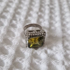 Ring - Justerbar ring med grön sten. Blivit aningen röd vid ringen men förstlr inte helheten.