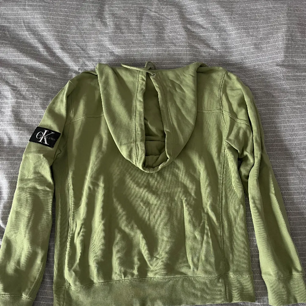 Ljusgrön Calvin Klein Hoodie med fastsydd patch med logga på ärmen. En aning oversized.  Nypris: 1099kr  Skick: Bra, använd några gånger, inga synliga brister  Säljs för att den inte passar mig. Hoodies.