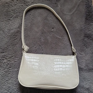 Liten vit väska, använd 1 gång  - Väskan är i väldigt nra skick då den bara är använd en gång. Den är rymligt samtidigt som den är liten. Köpare står för frakten om den ska skickas 