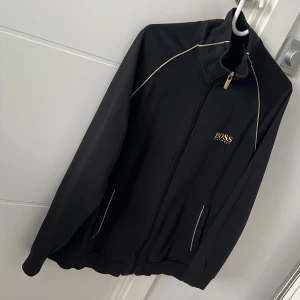 Har haft den ett tag men den är fortfarande i väldigt bra skick. - Hugo Boss Storlek: M Färg: Svart med Guld 