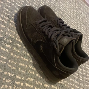 Nike Dunk Low Undefeated X AF1 - Nike Dunks Low  Undefeated x Aft svarta  Skick 9/10  Storlek 44 EU Kommer med extra sko snören  Inget kvitto tyvärr kommer utan boxen.  Säljer pga att dem är för små. Perfekta skor för våren och sommaren  Möts upp i Stockholm 