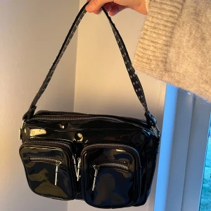 Noella väska  - Fin väska från noella. Svart lackad med silver detaljer. Bra fack och tillkommer även ett längre band. Nypris 1000kr💕Superfint skick! 