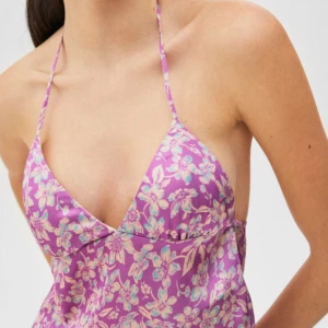 Pull&Bear purple floral halter top  - Toppen är i mycket bra skick använts ett fåtal gånger säljs av den anledning att den är för liten. Trots storlek L skulle jag säga att toppen är mindre än det, så ha det i åtanke. Pull&bears storlekar är mindre än vad man tänker sig.