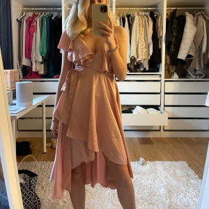 Ljusrosa klänning - Säljer denna jättefina omlottklänningen från Boohoo. Använd fåtal gånger så väldigt fint skick. 