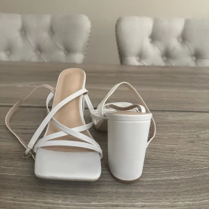 Klackskor i vit - Klackskor med band samt spänne. Använd 2 gånger.