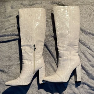 Vita klackar - Vita klackskor i fake ¿krockodil?. Storlek 38 men lite små så skulle säga 37 ist. Klack på ca 7/8 cm. tycker dom ger lite taylor swift vibes. Andvänd en gång inomhus.
