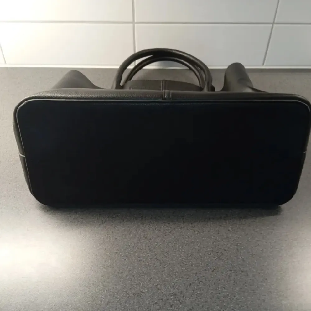 En svart väska i skinn imitation, får plats med verkligen allting 😍finns även ett långt band med . Väskor.