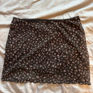 Mini kjol - Jättesöt minikjol med blommor och en liten rosett. Aldrig använd. 