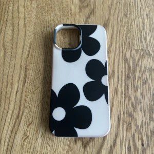 Skal 15 - Skal till iPhone 15 med svarta blommor. Lite skadat längst ner i vänstra hörnet (se bild 2) men syns knappt. 