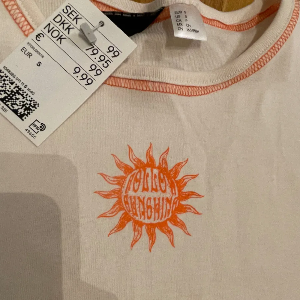 Vit t-shirt med orange detaljer. Är helt oanvänd och har prislappen kvar. Säljer för att den är fel storlek för mig. 🧡. T-shirts.