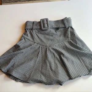 Rutig skort - Snygg svartvit rutig skort med bälte från Zara i storlek xs. Plagget är i en A-linjeform och har en bekväm passform.