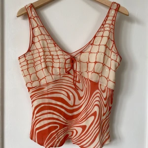 Orange och vit topp från Planet - En unik topp från Planet i orange och vit/orange färg. Den har en knytning framtill och är ärmlös🙌💓