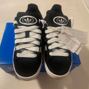 Nya Adidas Campus 00s -storlek 36 2/3, sista paret! - Adidas Originals Campus 00 s j 36 2/3 Svarta (Core Black/Cloud White/Cloud White) Ingår både vita och svarta skosnören.  Nya och oanvända. Ligger kvar i kartong.  Köpta i svensk webbutik och kommer inte från någon massimport utomlands. 