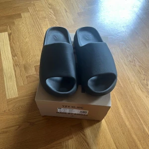 Yeezy slide - Nästan i nytt skick och har knappt använt dom.  Dom är generellt sett små i storleken, jag har 43 och dessa sitter bra på mig