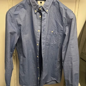 Blå NN07 skjorta  - Blå skjorta från NN07, storlek M. Använd fåtal gånger därav mycket fint skick. 