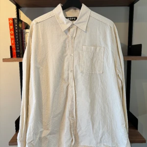 Hope Skjorta  - Hope skjorta en en oversized passform, färgen är vit med ett räfflat mönster med små gula detaljer 