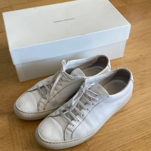 Common Projects sneakers - Vita skinnsneakers från Common Projects i storlek 41. (Stora i storlek så mer som 42). Nypris 3999:- Originalförpackning + nya snören och påse medföljer.  Dessa är använda men fortfarande i bra skick. 
