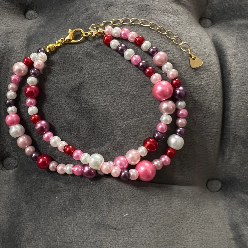 Egentillverkat armband med pärlor i två rader i olika rosa nyanser och guldigt spänne. Justerbar passform mellan 19-25 cm.. Accessoarer.