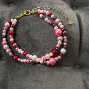 Pärlarmband  - Egentillverkat armband med pärlor i två rader i olika rosa nyanser och guldigt spänne. Justerbar passform mellan 19-25 cm.