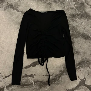 Svart topp - Kan justera hur kort man vill ha tröjan på grund av trådarna i mitten. Super fin till sommaren. Ribbad.