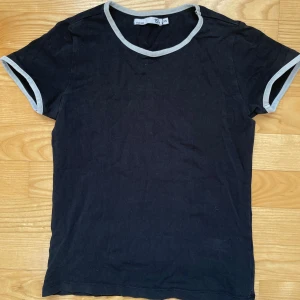Svart t-shirt - Säljer denna t-shirt då den blivit för liten, använd men i jättefint skick! Fina vita detaljer. Den passar XXS-XS beroende på hur man vill att den ska sitta😇Hör gärna av dig vid frågor/intresse/för fler bilder eller för att diskutera priset!