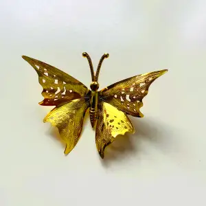 Vacker guldfärgad fjärilsbrosch med dekorerade vingar   Okänd metall 
