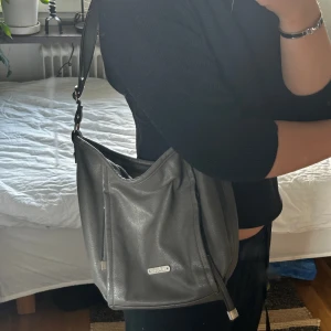 Grå väska - Skit snygg grå väska från Kappahl! Har knutit upp banden så den går att få längre. Den har fack, mycket plats och super snygg!