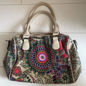 mönstrad väska  - En mönstrad väska köpt secondhand. Fin och mycket utrymme! Finns även extrafickor både inne och ute 😊 Om du har någon fråga eller vill ha en extrabild så kontakta så fixar jag!! OBS: liten fläck på innefodret annars fint begagnat skick