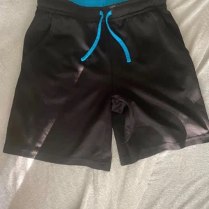 Shorts strl 140  - Strl 140 ca 10 år  Kläder/shorts  till skolans idrott Fint skick Svarta med blått band  