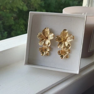 Guldörhängen med blommor - Så fina guldfärgade örhängen. Helt oanvända, säljer då dem aldrig har kommit till användning.