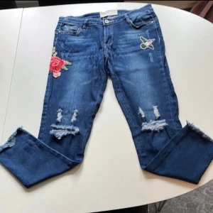 Jeans med broderade detaljer. - Snygga jeans med broderade detaljer.Hål på knän samt fransar nertill.