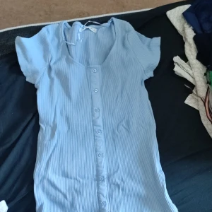 Ribbad tshirt  - Ribbad tshirt med knappar som ej går att öppna i storlek medium 