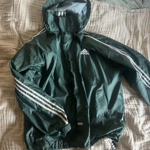 Adidas - Retro adidas vindjacka i grön förg. Jag är 1.78 och den är lång i ärmarna på mig. Storleken är oklar men passar allt från S-L för en kvinna och S-M för en kille 