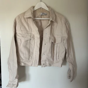Jeans jacka i beige  - En fin jeans jacka i beige till sommaren!☀️ Kortare i modellen. Den har fickor på sidorna samt bröstfickor. En knapp har låstnat på höger arm. Se bild. ❤️