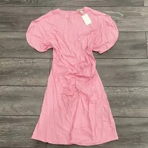 Rosa klänning med en ihopsydd detalj Prislappen är kvar och den är aldrig använd. hör av dig om du vill ha fler bilder eller om du har några funderingar💝