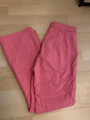 Rosa byxor - Ett par av mina favoritbyxor som blivit försmå. Rosa kostymbyxor med fickor vid fram. Utsvängda längst ner. Passar inte till längre människor